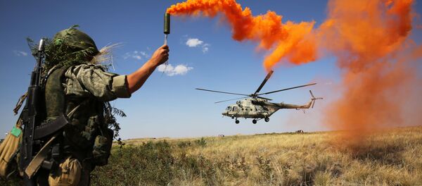 Militar russo participa das manobras táticas do Distrito Militar Sul no polígono de Prudboi, na região de Volgogrado, junto a um helicóptero militar Mi-8 - Sputnik Brasil