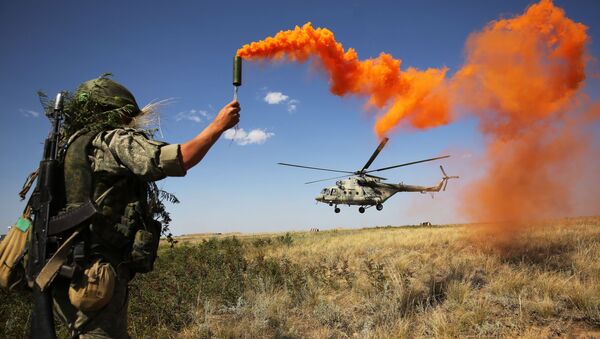 Militar russo participa das manobras táticas do Distrito Militar Sul no polígono de Prudboi, na região de Volgogrado, junto a um helicóptero militar Mi-8 - Sputnik Brasil