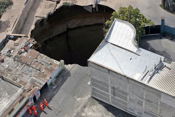 Vista aérea de uma enorme cratera de 60 metros de profundidade que surgiu no centro da Cidade de Guatemala, engolindo um prédio - Sputnik Brasil