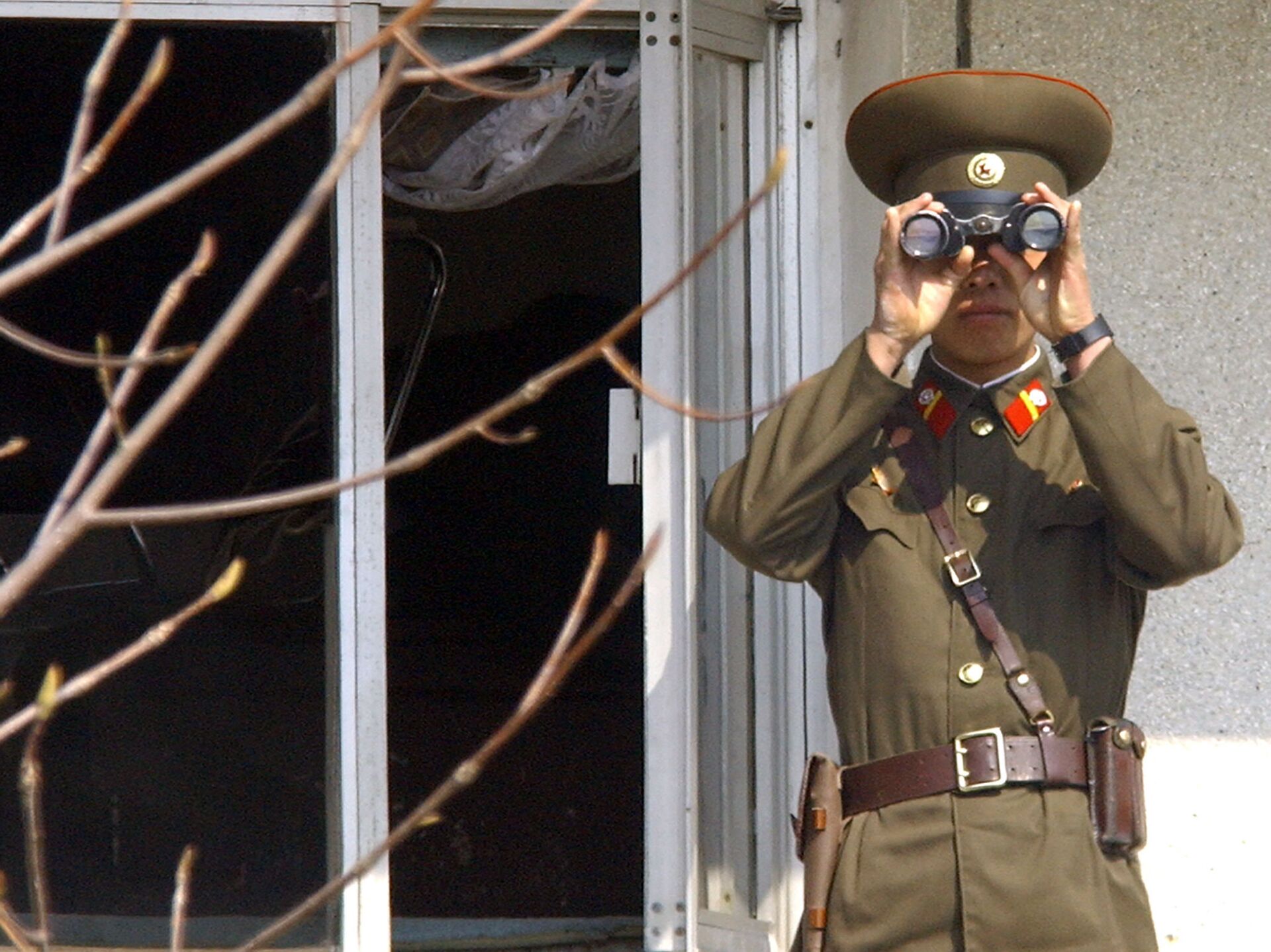 Soldado norte-coreano olha para o lado sul através de binóculos na vila fronteiriça de Panmunjom, na zona desmilitarizada que divide a Coreia do Norte e a Coreia do Sul, em 13 de abril de 2005
