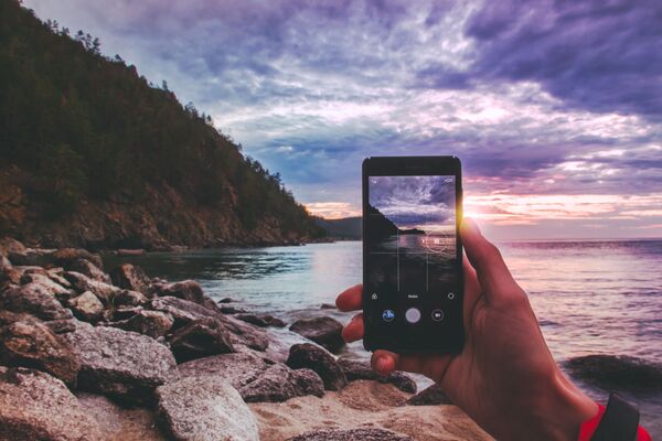 Celular tira foto da magnífica paisagem do lago Baikal (sul da Sibéria), através do qual é possivel ver o pôr do sol e parte da montanha - Sputnik Brasil