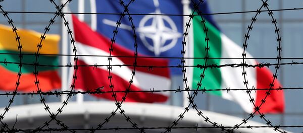 A bandeira da OTAN é vista através de arame farpado tremulando em frente à nova sede da aliança em Bruxelas, na Bélgica. - Sputnik Brasil