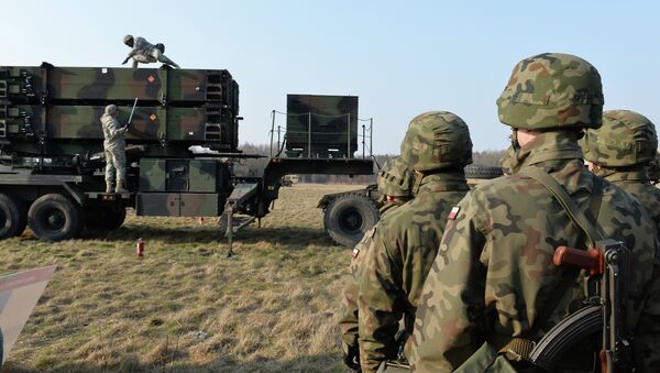 Polish soldiers watch as US troops from the 5th Battalion of the 7th Air Defense Regiment emplace a launching station of the Patriot air and missile defence system at a test range in Sochaczew, Poland, on March 21, 2015. - Sputnik Brasil
