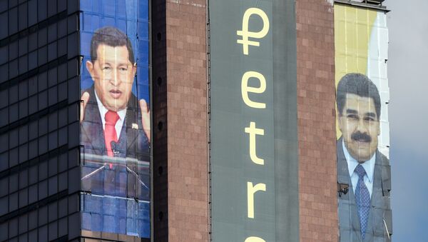 Logotipo do petro é exibido ao lado das imagens do falecido presidente venezuelano Hugo Chávez e do atual líder do país, Nicolás Maduro, em um prédio no centro de Caracas, em 21 de setembro de 2018 - Sputnik Brasil