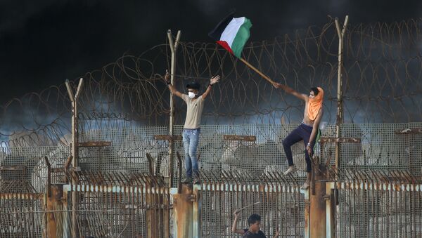 Manifestantes palestinos desfraldam bandeira na fronteira entre Israel e a Faixa de Gaza - Sputnik Brasil