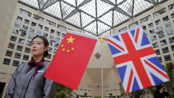 Um membro da equipe de pé atrás de bandeiras enquanto os oficiais chegam para a Mesa Redonda de Serviços Financeiros de Alto Nível Reino Unido-China no prédio da sede do Banco da China em Pequim (arquivo). - Sputnik Brasil