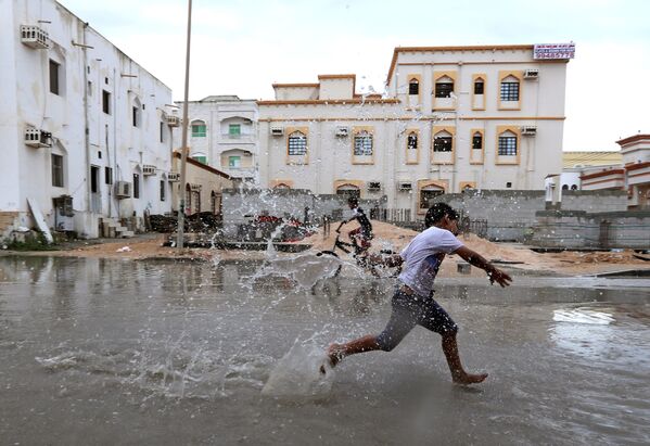 Crianças brincam em uma rua de Omã inundada pelo ciclone tropical Luban - Sputnik Brasil
