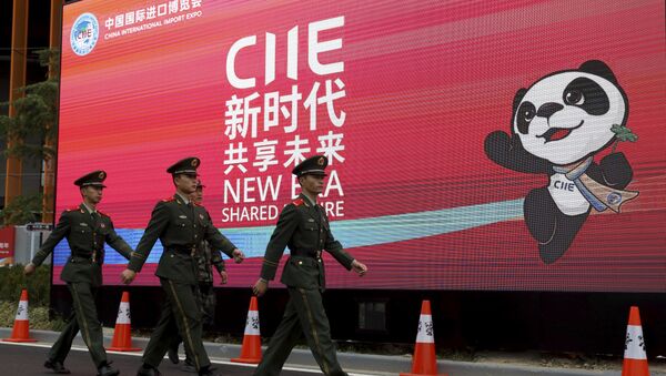 Policiais marcham em frente a uma propaganda da China International Import Expo durante a abertura da feira de negócios em Xangai, China. - Sputnik Brasil