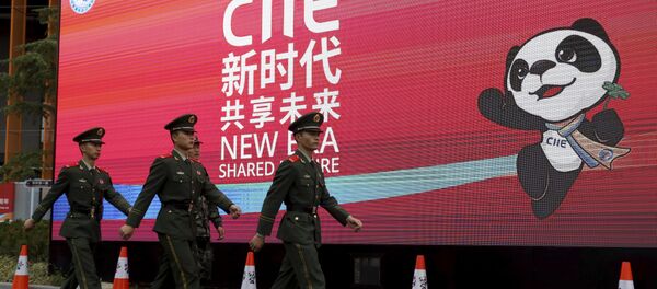 Policiais marcham em frente a uma propaganda da China International Import Expo durante a abertura da feira de negócios em Xangai, China. - Sputnik Brasil