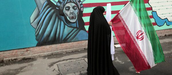 Mulher iraniana segura bandeira nacional enquanto passa por um muro representando a Estátua da Liberdade na parede da antiga embaixada dos EUA em Teerã (foto de arquivo) - Sputnik Brasil