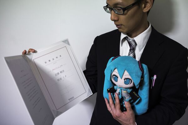 Akihiko Kondo mostra a certidão de casamento, após se casar com a cantora virtual Hatsune Miku, segurando uma boneca dela - Sputnik Brasil