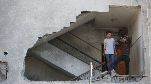 Moços palestinos em um prédio residencial semi-destruído por um ataque aéreo israelense na Faixa de Gaza - Sputnik Brasil