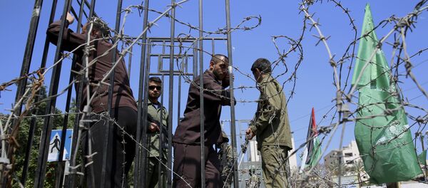 Masked militants from the Izzedine al-Qassam Brigades, a military wing of Hamas, stand guard near a mockup of a prison cell during a rally marking Palestinian prisoners Day, in Gaza City, Monday, April 17, 2017 - Sputnik Brasil