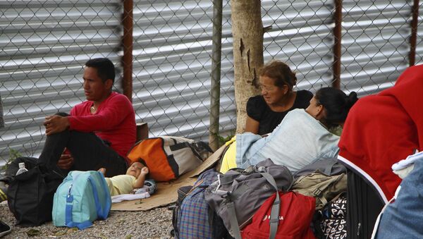 Imigrantes venezuelanos descansam ao lado de seus pertences após cruzarem a fronteira até Pacaraíma, em Roraima. - Sputnik Brasil