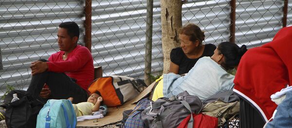 Imigrantes venezuelanos descansam ao lado de seus pertences após cruzarem a fronteira até Pacaraíma, em Roraima. Imigrantes venezuelanos descansam ao lado de seus pertences após cruzarem a fronteira até Pacaraíma, em Roraima. - Sputnik Brasil