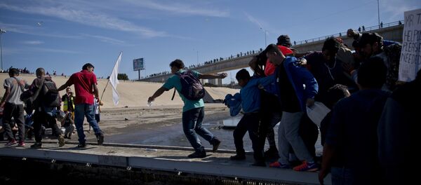 Migrants cross the river at the Mexico-U.S. border after getting past a line of Mexican police at the Chaparral crossing in Tijuana, Mexico, Sunday, Nov. 25, 2018 - Sputnik Brasil