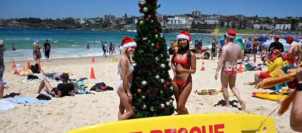 Turistas posam para foto usando gorro de Papai Noel ao lado de uma árvore de Natal na praia de Bondi em Sydney, em 25 de dezembro de 2018 - Sputnik Brasil