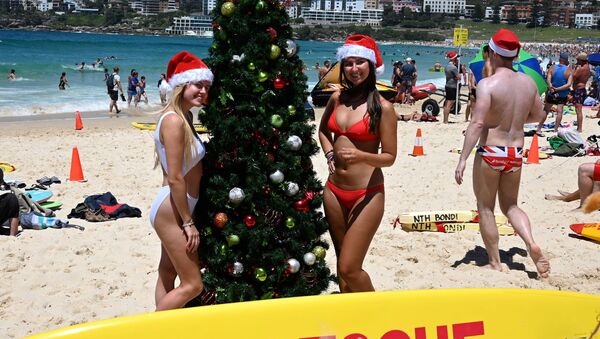 Turistas posam para foto usando gorro de Papai Noel ao lado de uma árvore de Natal na praia de Bondi em Sydney, em 25 de dezembro de 2018 - Sputnik Brasil