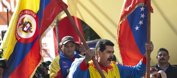 Venezuela's President Nicolas Maduro holds up a Colombian national flag, left, alongside his country's national flag, during a rally in support of closing the Colombian border, in Caracas, Venezuela, Friday, Aug. 28, 2015. - Sputnik Brasil