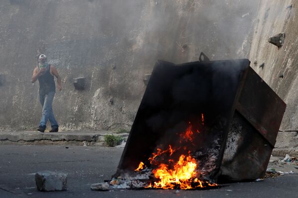 Manifestante por trás de uma barricada em chamas durante protestos em Caracas, Venezuela - Sputnik Brasil