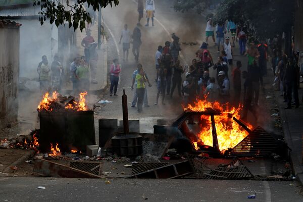 Manifestantes por trás de uma barricada em chamas durante protestos em Caracas, Venezuela - Sputnik Brasil