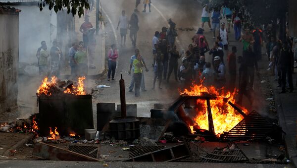 Manifestantes por trás de uma barricada em chamas durante protestos em Caracas, Venezuela - Sputnik Brasil