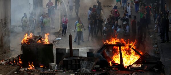 Manifestantes por trás de uma barricada em chamas durante protestos em Caracas, Venezuela - Sputnik Brasil