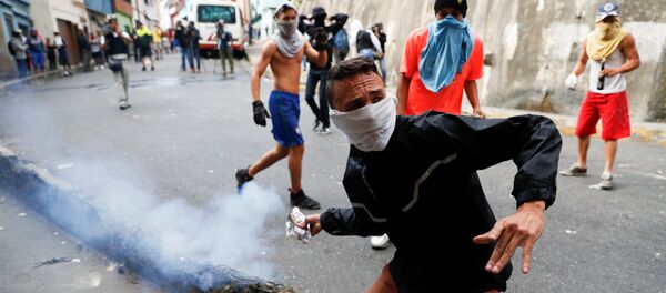 Manifestante joga bomba de gás lacrimogêneo de volta contra Guarda Nacional venezuelana durante protesto em Caracas, Venezuela, em 21 de janeiro de 2019 - Sputnik Brasil