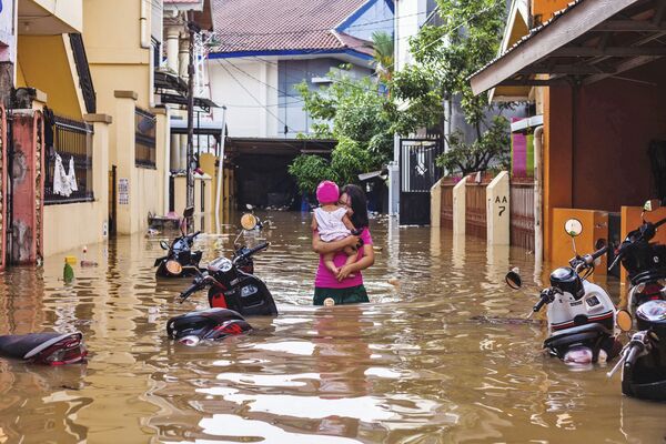 Mulher carrega criança em uma rua inundada na cidade indonésia de Makasar, 23 de janeiro de 2019 - Sputnik Brasil
