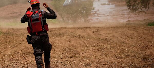 Um bombeiro gesticula perto de um helicóptero de resgate após uma barragem de rejeitos da mineradora brasileira Vale SA explodir em Brumadinho. - Sputnik Brasil