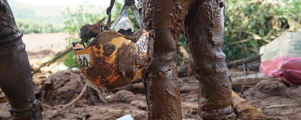 No detalhe, o capacete coberto de lama de uma oficial dos Bombeiros que trata na busca por corpos em Brumadinho, MG. - Sputnik Brasil