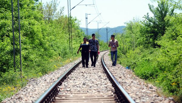 Refugiados seguem as trilhas de uma estrada de ferro perto da fronteira entre a Grécia e a Macedônia - Sputnik Brasil