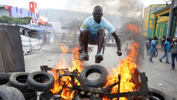 Manifestante salta sobre uma barricada em chamas durante protesto contra o governo nas ruas de Porto Príncipe, no Haiti, em 10 de fevereiro de 2019 - Sputnik Brasil
