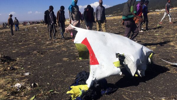 Pessoas passam por parte dos destroços no local do acidente de avião do voo ET302 da Ethiopian Airlines, perto da cidade de Bishoftu, a sudeste de Adis Abeba, Etiópia, 10 de Março de 2019 - Sputnik Brasil