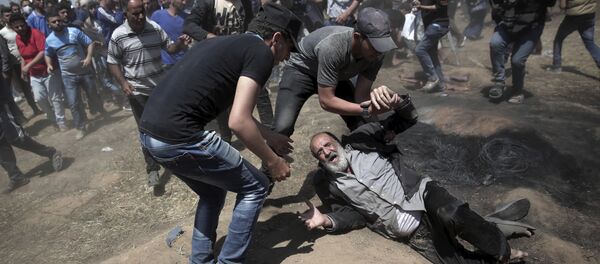 Um palestino idoso cai no chão depois de ser baleado por tropas israelenses durante um protesto na fronteira da Faixa de Gaza com Israel. - Sputnik Brasil