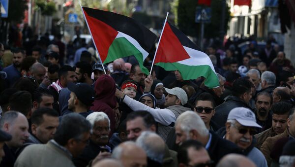 Palestinos seguram bandeiras nacionais em marcha pelas ruas da cidade ocupada de Ramallah pedindo pela unificação da cidade à Faixa de Gaza, 12 de janeiro de 2019 - Sputnik Brasil