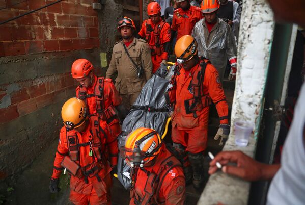 Equipes de resgate transportam corpo encontrado em uma área de deslizamento de terra em decorrência de fortes chuvas no Rio de Janeiro - Sputnik Brasil