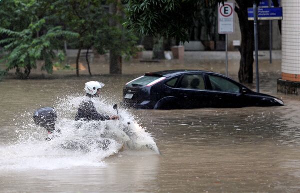 Motociclista anda por rua alagada em decorrência de fortes chuvas no Rio de Janeiro - Sputnik Brasil