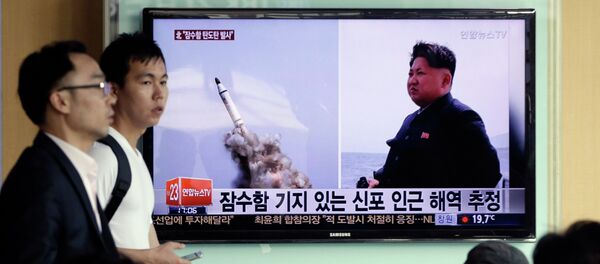 Programa de TV na Coreia do Sul mostra images veiculadas pelo jornal norte-coreano Rodong Sinmun do suposto lançamento submarino de um míssil balístico da Coreia do Norte, ao lado do líder norte-coreano Kim Jong-un, em 9 de maio de 2015 - Sputnik Brasil