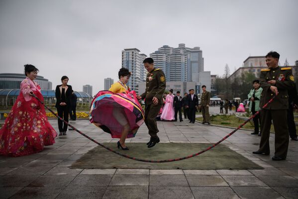 Noivos pulam corda durante sessão de fotos de casamento em um parque de Pyongyang, Coreia do Norte, 18 de abril de 2019 - Sputnik Brasil