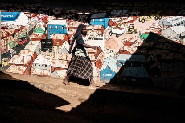 Mulher passa por parede com grafites nas favelas de Kibera, em Nairobi, 16 de abril de 2019 - Sputnik Brasil