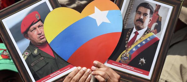 Apoiador(a) do presidente venezuelano, Nicolás Maduro, exibe imagens do atual chefe de Estado e de seu antecessor, Hugo Chávez, durante manifestação em Caracas no Dia do Trabalhador - Sputnik Brasil