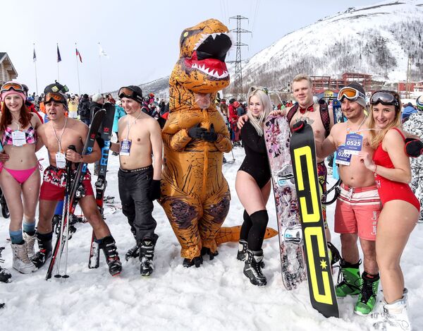 Participantes posam para foto ao lado de uma pessoa fantasiada de dinossauro no festival Khibiny-Bikini 2019, na cidade de Kirovsk, Rússia - Sputnik Brasil