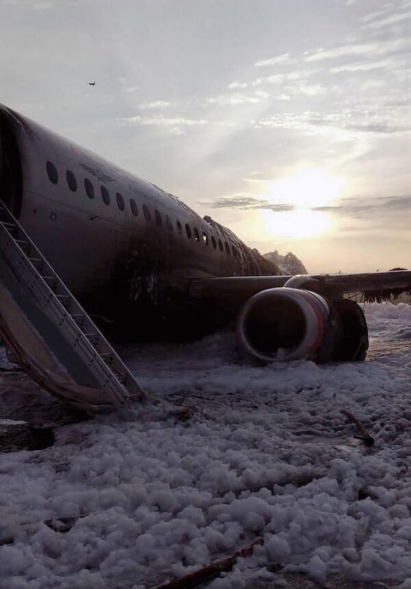 Escombros do avião SSJ100 na pista de aterrissagem no Aeroporto Sheremetyevo vistos após bombeiros apagarem o fogo - Sputnik Brasil