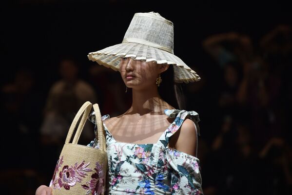 Com sombreiro e bolsa praieira, modelo desfila usando vestido com estampa de flores da nova coleção do estilista australiano Tigerlily na Austrália Fashion Week, em Sydney - Sputnik Brasil
