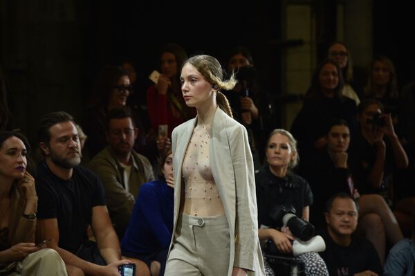Modelo desfila usando uma blusa transparente por dentro de casaco que combina com calça da nova coleção de Karla Spetic - Sputnik Brasil