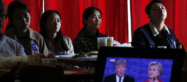Estudantes chineses assistem a transmissão ao vivo do debate presidencial entre a candidata democrata Hillary Clinton e o candidato republicano à presidência, Donald Trump, em um café em Pequim. - Sputnik Brasil