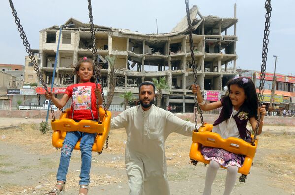 Meninas brincam perto de edifício danificado no primeiro dia do feriado muçulmano Eid al-Fitr, em Raqqah, Síria - Sputnik Brasil