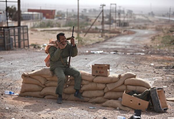 Militante armado fala pelo celular no posto de controle na cidade de Brega, situada no leste da Líbia e controlada pelos rebeldes  - Sputnik Brasil