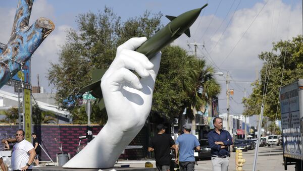 A escultura Jogo Perigoso do artista italiano Lorenzo Quinn, à direita, à mostra em Wynwood, em Miami, nos EUA. A escultura mostra uma mão segurando um míssil como um dardo. Foto de 8 de dezembro de 2017. - Sputnik Brasil